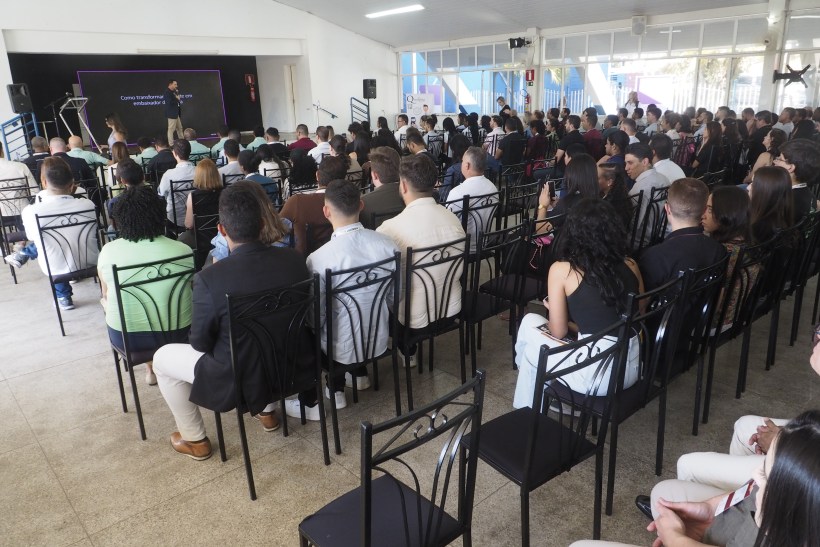 Plateia cheia durante uma palestra no Super Encontro Varejista (Sevar) em Divinópolis, com um apresentador no palco e participantes atentos.