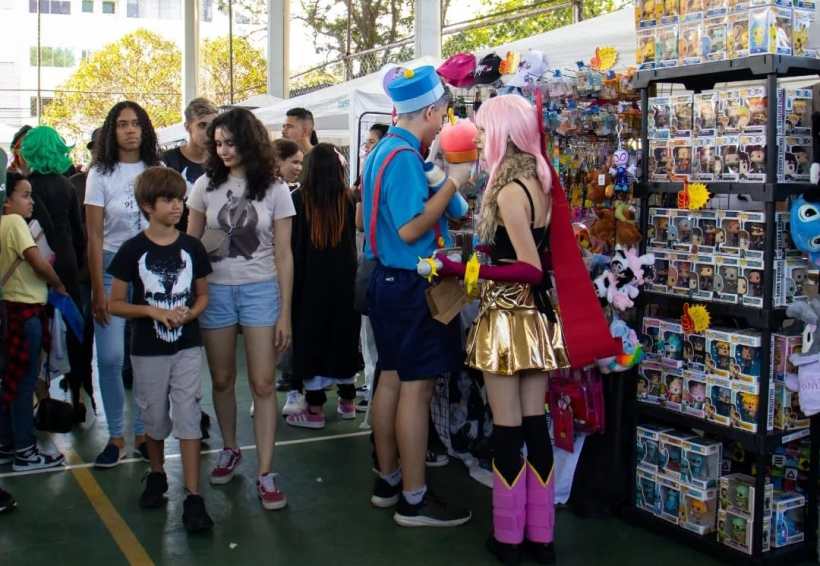Pessoas interagem em uma feira de cultura pop oriental, com destaque para a variedade de produtos em exibição, incluindo figuras de ação e itens de cosplay.