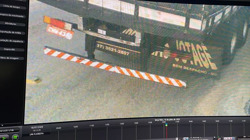 Imagem de câmera mostrando a parte traseira de um caminhão, com placas de identificação parcial e um suporte refletivo listrado em vermelho e branco.