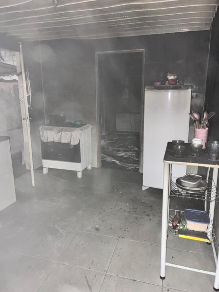 Cozinha com densa fumaça, refletindo um possível incêndio, sem chamas visíveis.