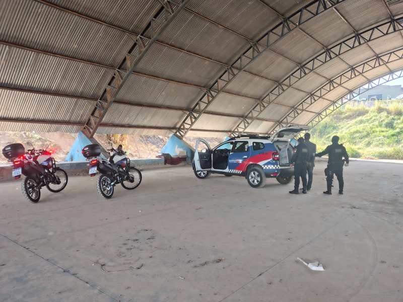 Equipe da Guarda Civil Municipal em patrulhamento em área coberta, com motocicletas e um veículo policial estacionado.