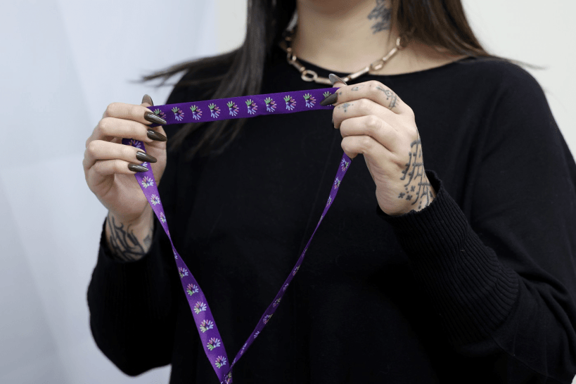 Pessoa segurando um cordão de fita roxa com desenhos de flores, simbolizando a identificação de pessoas com doenças raras.