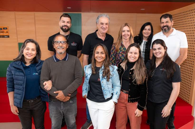 Grupo de pessoas sorrindo em um ambiente interior, posando para foto em um evento relacionado à responsabilidade social.