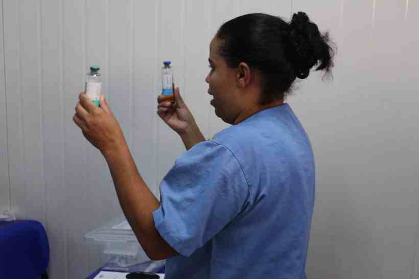 Profissional da saúde segurando frascos de medicamentos durante treinamento sobre Protocolo de Sepse na UPA Divinópolis.