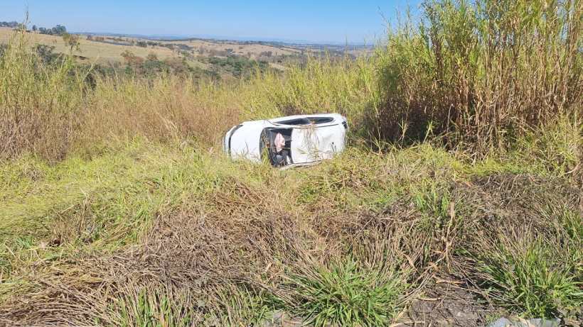 Um veículo VW Gol capotado em um campo, cercado por grama alta, após um acidente de trânsito na Rodovia BR 354.