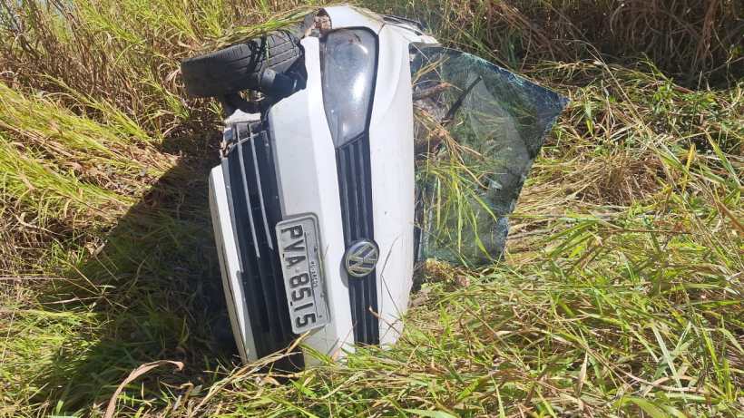 Veículo VW Gol capotado na margem esquerda da BR 354, cercado por grama alta.