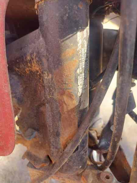 Close-up image of a rusted motorcycle frame part, showing corrosion and damaged identification markings.