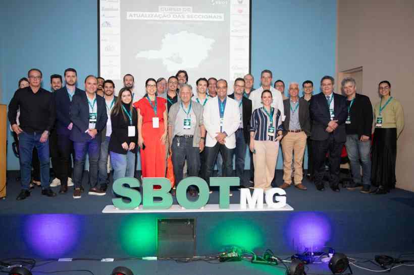 Grupo de profissionais da saúde reunidos no Curso de Atualização das Seccionais da SBOT-MG, com destaque para o letreiro 'SBOT MG' em primeiro plano.