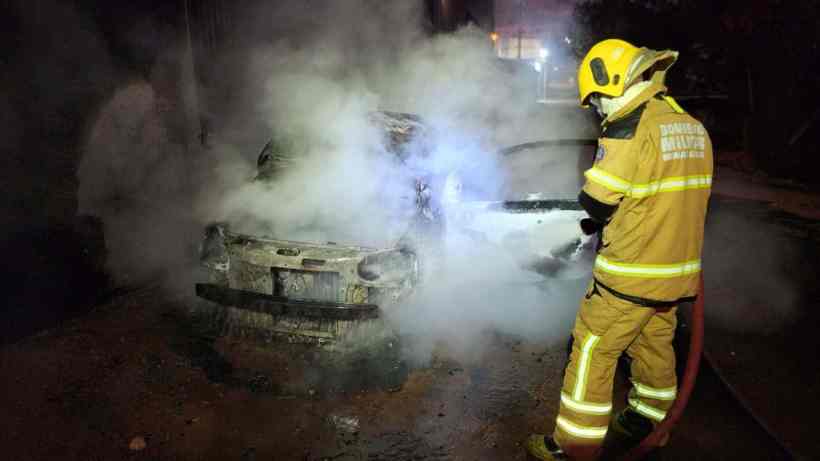 Bombeiro combatendo incêndio em um veículo envolto em fumaça.