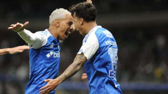 Jogadores do Cruzeiro comemorando um gol durante uma partida, expressando alegria e empolgação.