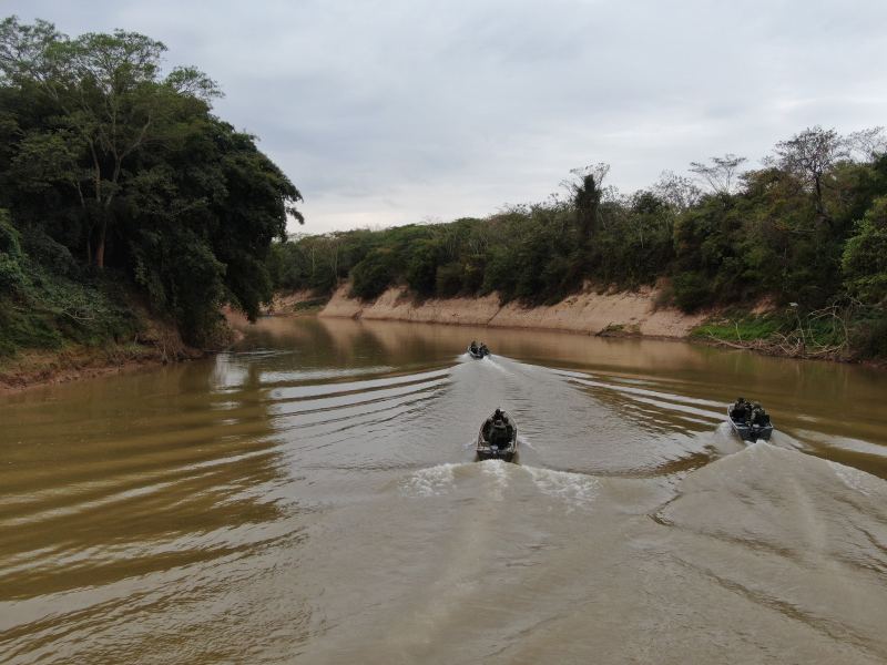 Três embarcações da Polícia Militar navegando pelo Rio São Francisco, cercadas por vegetação e margens de areia.