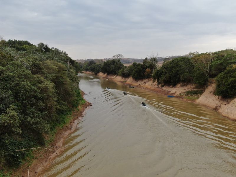 Vista aérea do Rio São Francisco com três embarcações em operação de fiscalização ambiental, cercadas por vegetação nas margens.