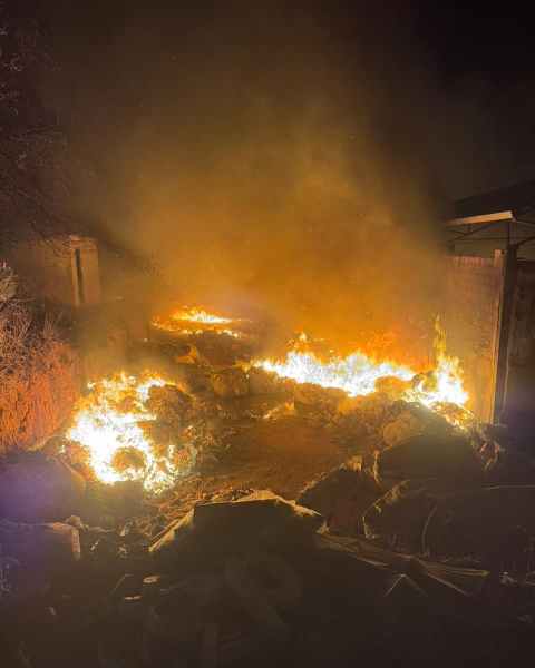 Incêndio em área de disposição de resíduos sólidos, com chamas intensas e fumaça visible, durante a noite.