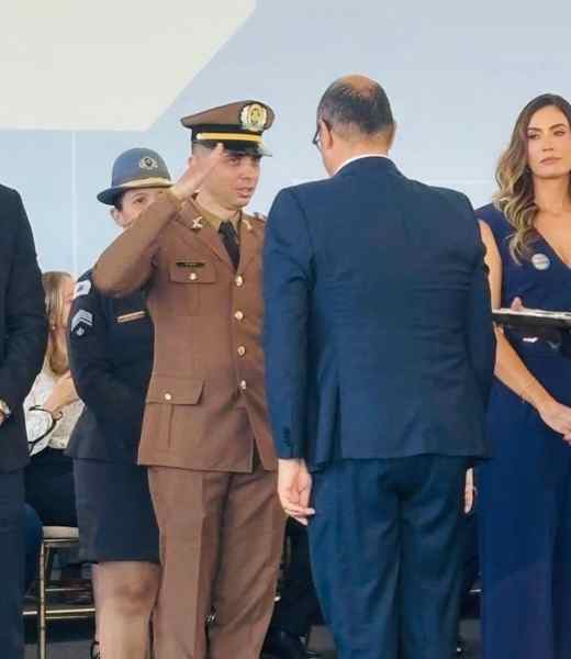 Cabo Lucas Costa Neto sendo condecorado com a Medalha Presidente Juscelino Kubitschek em cerimônia realizada em Diamantina, acompanhado por autoridades e colegas.