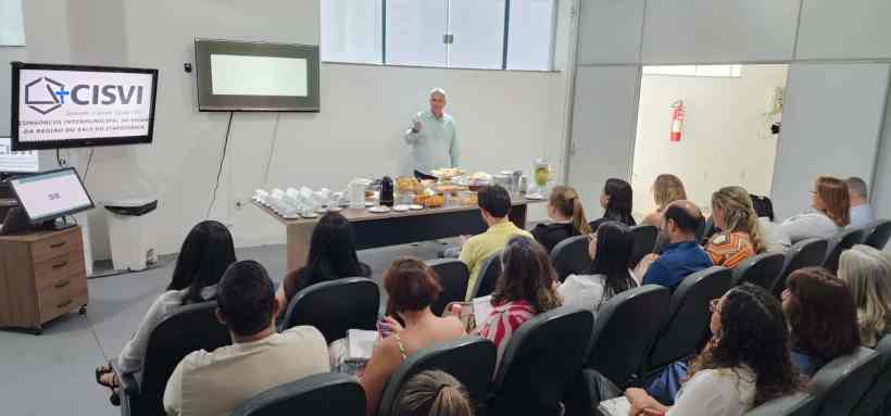 Evento de integração entre secretários municipais de saúde no CISVI em Divinópolis, com mesa de café e apresentação em destaque.