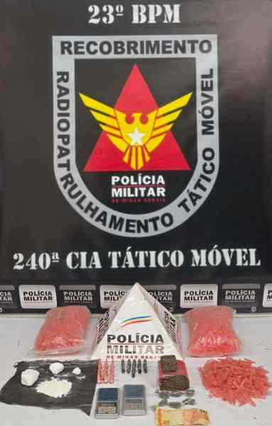 Imagem da apreensão realizada pela Polícia Militar, com drogas e munições dispostas em uma mesa, ao fundo aparece o emblema da corporação.