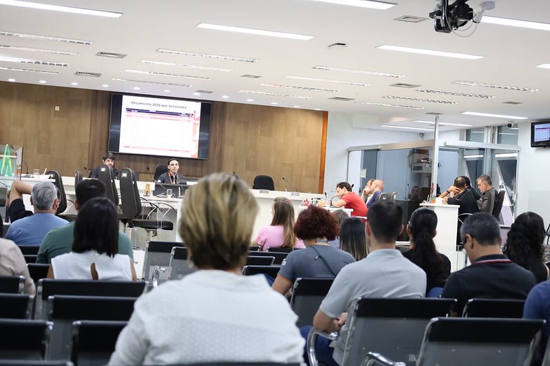 Audiência pública na Câmara Municipal de Divinópolis, com cidadãos ouvindo a apresentação do orçamento previsto para 2026 e o Plano Plurianual, destacando a participação popular e a transparência.