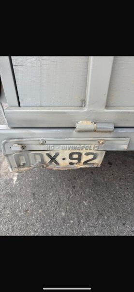 Close-up of a trailer's rear license plate in Divinópolis, showing signs of possible alterations with missing digits and irregular markings.