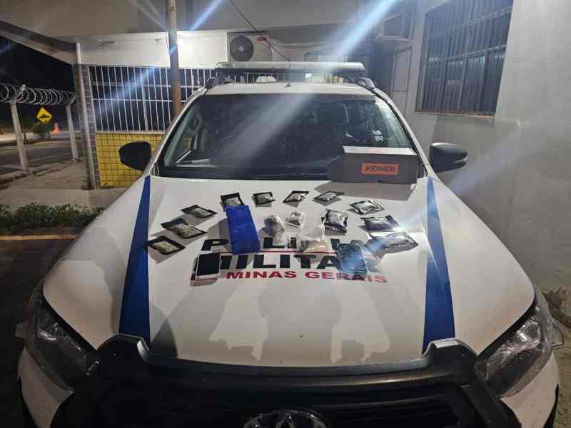 Veículo da Polícia Militar de Minas Gerais com entorpecentes apreendidos, incluindo porções de maconha e cocaína, disposto sobre o capô do carro.