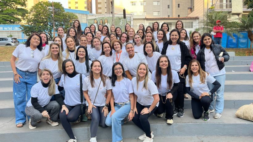 Group photo of a diverse group of women gathered together on outdoor steps, all wearing white shirts, smiling and posing for the camera.