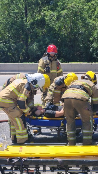 Equipe de bombeiros realizando atendimento a vítima durante simulado de acidente com produtos perigosos em rodovia.