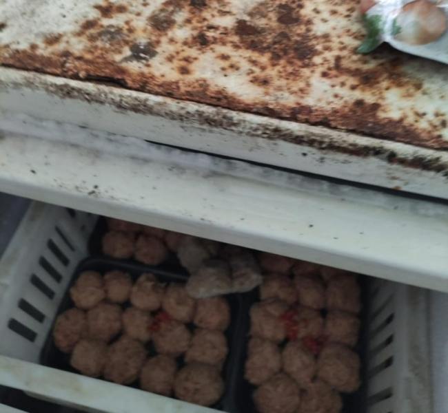 Interior de um freezer sujo com carne moldada e embalagens desorganizadas, evidenciando condições inadequadas de armazenamento.