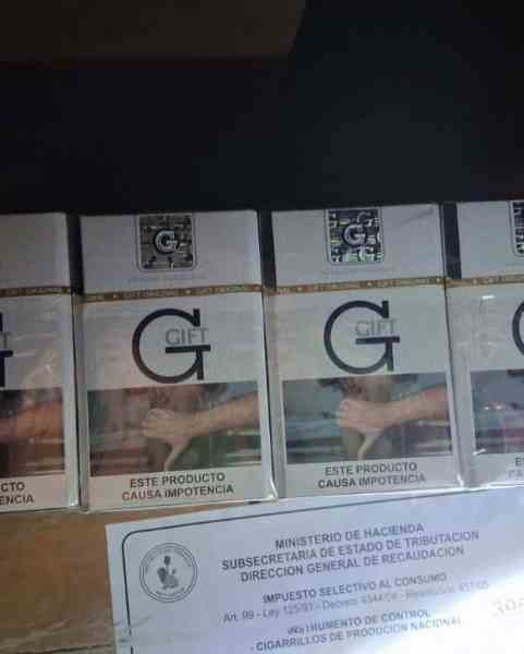 Caixas de cigarro contrabandeado da marca 'GIFT' com aviso de advertência sobre riscos à saúde.