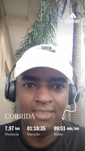 Imagem de um corredor usando fones de ouvido e boné, posando para a câmera ao ar livre. Informações sobre a corrida incluem 7,97 km de distância, duração de 1 hora e 18 minutos e ritmo de 9 minutos e 51 segundos por km.