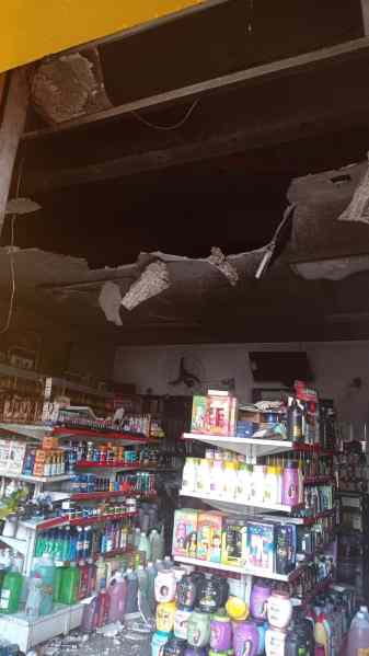 Interior de uma loja de cosméticos com prateleiras destruídas e um buraco no teto, evidenciando danos causados por incêndio.
