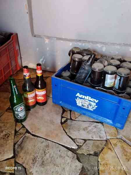 Bottles of alcoholic beverages arranged on the floor, including a crate containing multiple bottles and a few loose bottles, on a tiled surface.