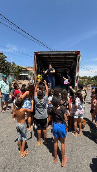 Crianças se aglomeram em frente a um caminhão, enquanto recebem brinquedos e doces durante uma ação social do projeto 'Big Brother do Bem'.