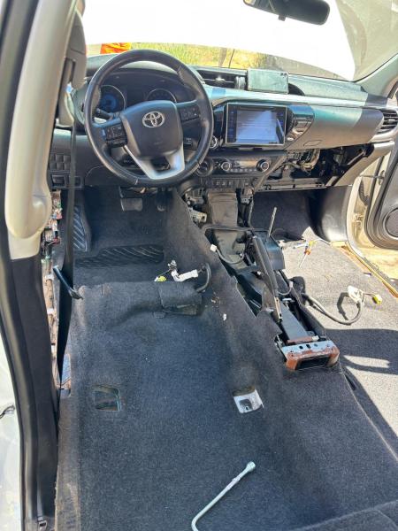 Interior de um carro com os bancos e a caixa do câmbio desmontados, exibindo o assoalho nu e o painel de controle visível.