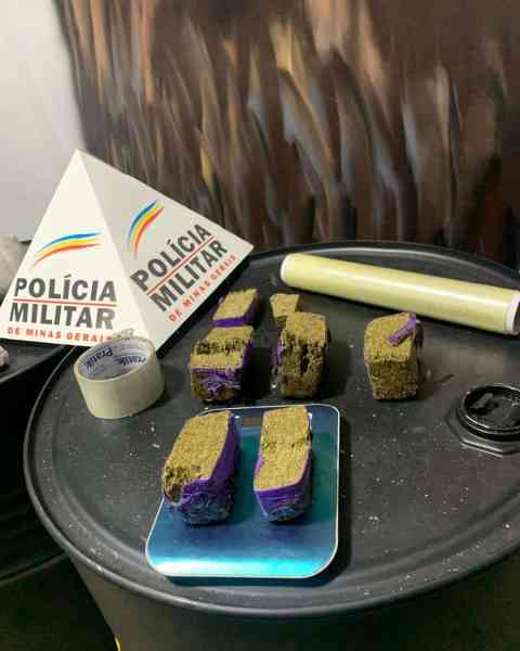Material apreendido pela Polícia Militar, incluindo tabletes de entorpecentes, rolo de plástico filme e fita adesiva sobre uma superfície.