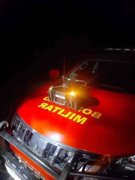 Close-up of a military fire truck with bright orange light on the hood, taken at night.