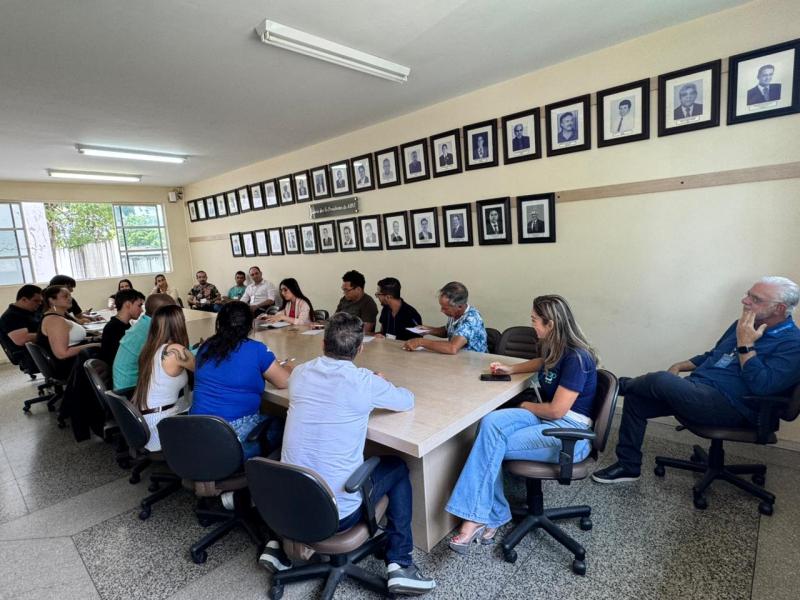 Grupo de pessoas reunidas em uma sala de conferências, participando de um curso sobre captação de recursos, com quadros de retratos ao fundo.