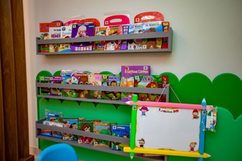Estante com livros e materiais educativos voltados para crianças, exibindo diversos títulos e personagens em um ambiente colorido e acolhedor.