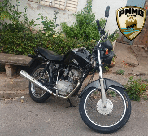 Motocicleta Honda/CG preta abandonada durante operação policial em Formiga, com logotipo da Polícia Militar de Minas Gerais ao canto.