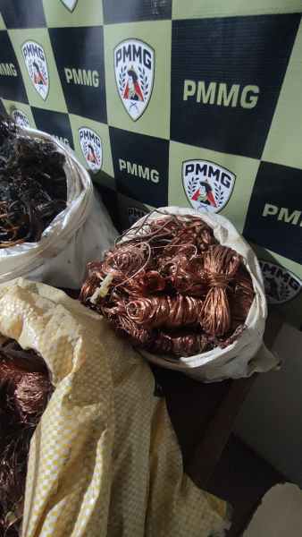Bolsas contendo fios de cobre apreendidos pela Polícia Militar, com logotipo da corporação em segundo plano.
