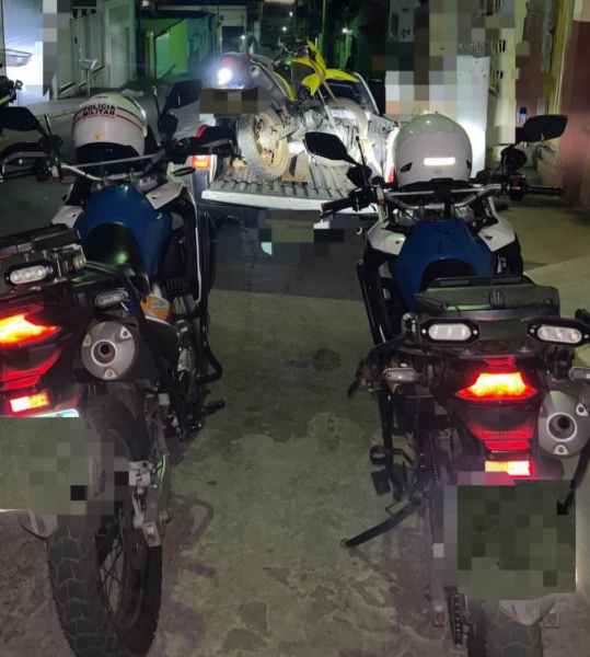 Motocicletas da Polícia Militar em operação, com uma motocicleta amarela sendo rebocada ao fundo.