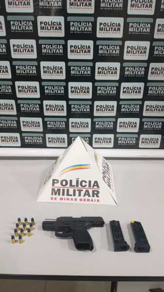 Uma pistola calibre .38, carregadores e munições dispostos sobre uma mesa, com um fundo que menciona a Polícia Militar de Minas Gerais.