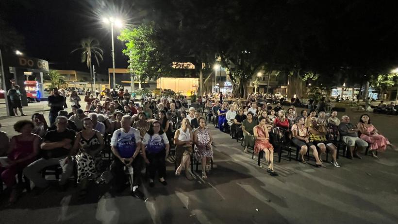 Público reunido na Praça da Catedral durante a terceira edição do Seresta na Praça, à noite, com árvores iluminadas ao fundo.
