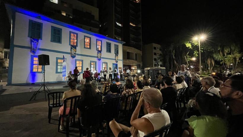 Público reunido assistindo a apresentação na Praça da Catedral durante a terceira edição do Seresta na Praça, com um grupo musical no palco e uma arquitetura colonial ao fundo iluminada à noite.