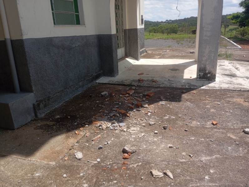 Área externa da igreja com destroços de tijolos e cimento no chão, após danos causados por ventos fortes.