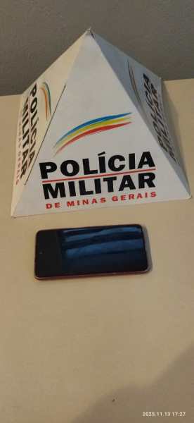 Aparelho celular recuperado ao lado de uma barreira triangular com a inscrição 'Polícia Militar de Minas Gerais'.