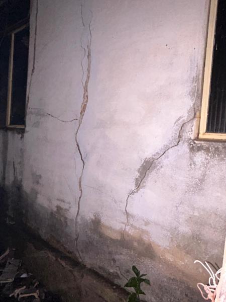 Paredes exteriores de um imóvel abandonado com fissuras visíveis e danos estruturais.