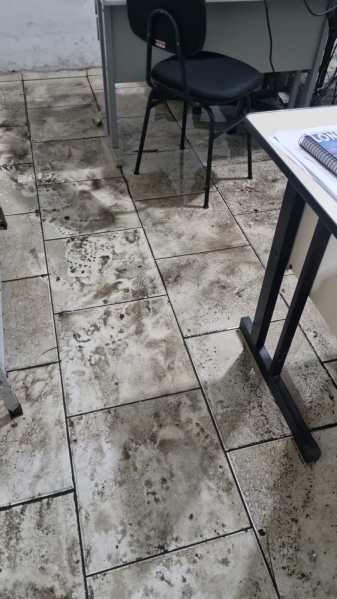 Piso de um ambiente interno mostrando marcas de lama e sujeira, indicando danos causados por alagamento.