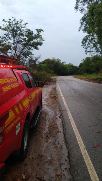 Veículo do Corpo de Bombeiros estacionado ao lado de uma estrada, com vegetação ao fundo e céu nublado.