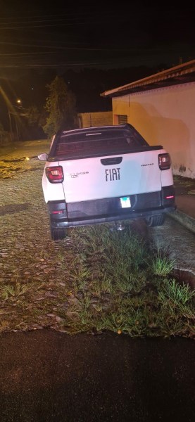 Caminhonete Fiat Strada Volcano estacionada em área suspeita à noite, com grama ao redor.