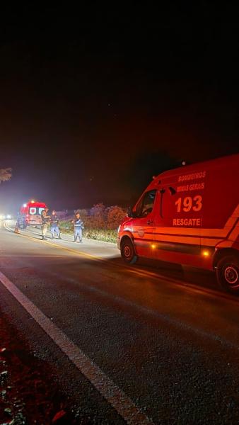 Emergency responders at night near a roadside with a rescue vehicle and flashing lights.