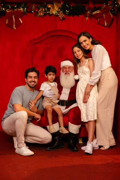 Uma família posando com o Papai Noel em um cenário natalino, cercada por decorações festivas.